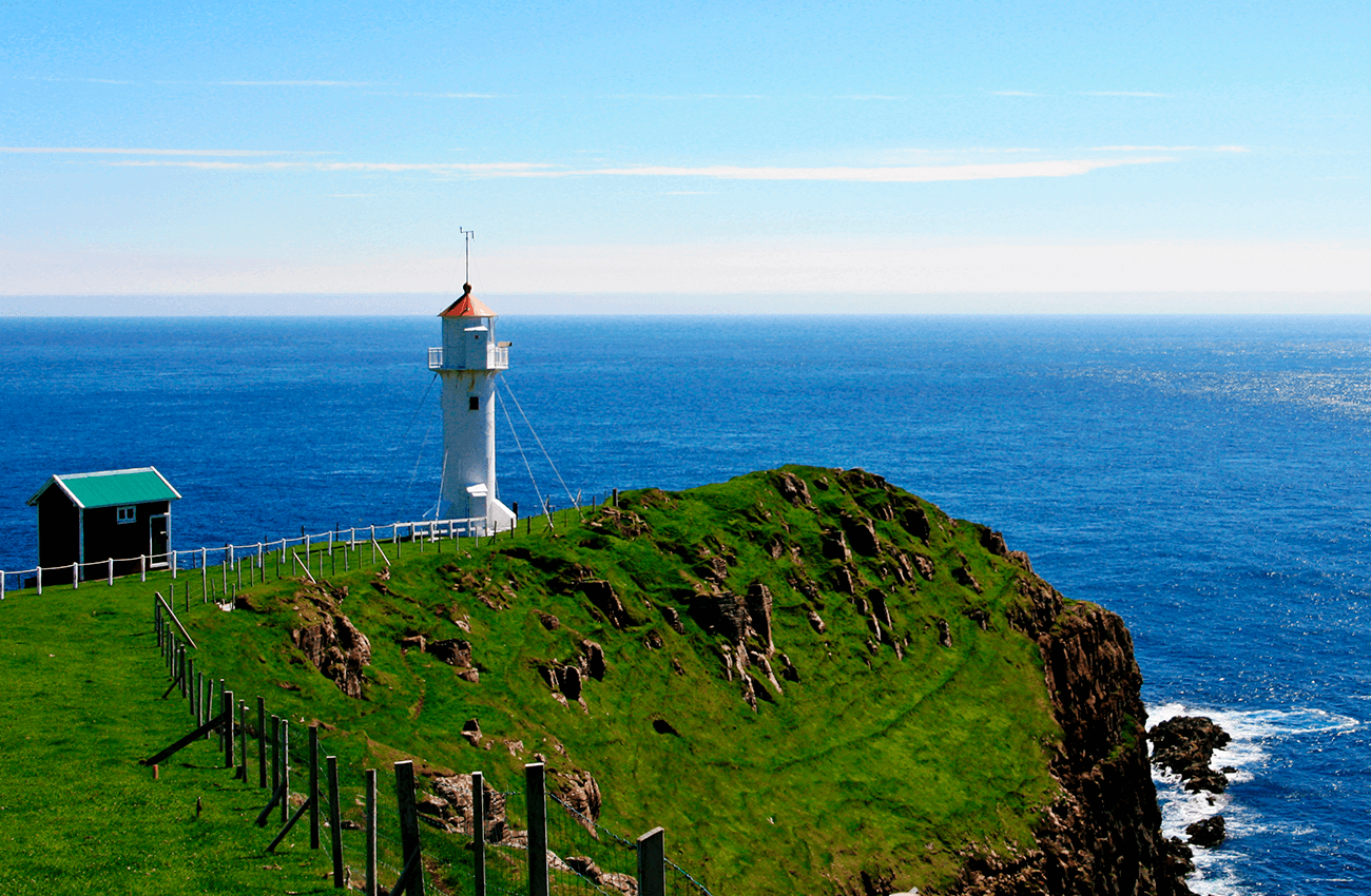 Billede af en fyrtårn på en klippe på en solrig dag i Akraberg på Færøerne.