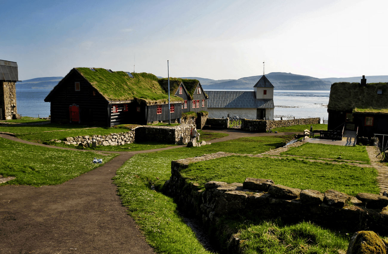 Billede af nogle sorte huse med mos på tagene i Kirkjubøur på Færøerne.