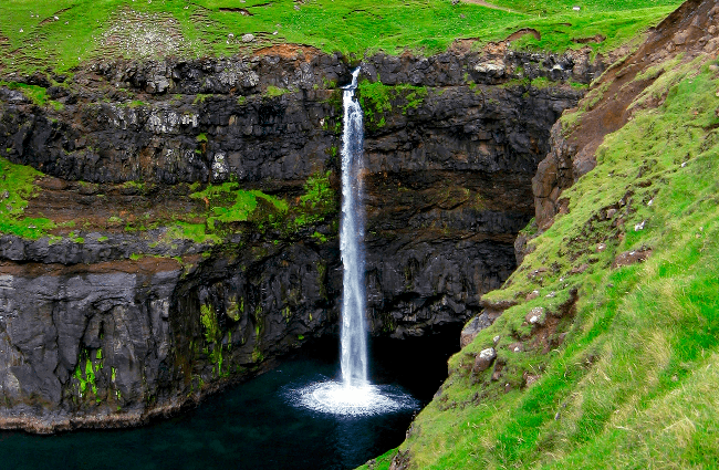 Billede af Mulafossur Vandfald, der går ud til havet på Færøerne.