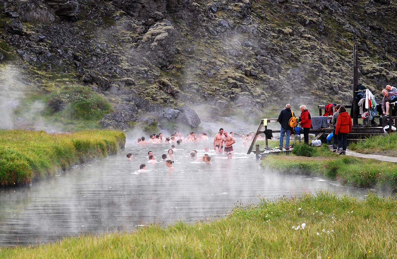 Billede af mennesker der bader i varmekilder i Landmannalaugar på Island.