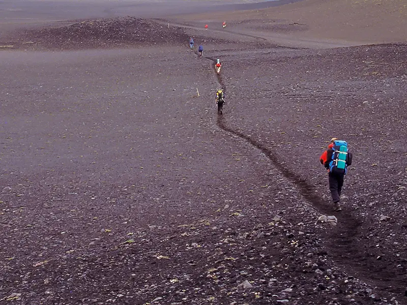 Turist vandrer gennem bjerglandskab ved Laugavegur i Island