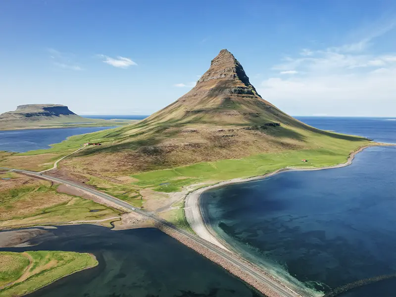 Bjergtoppen Kirkjufell på Island omgivet af hav