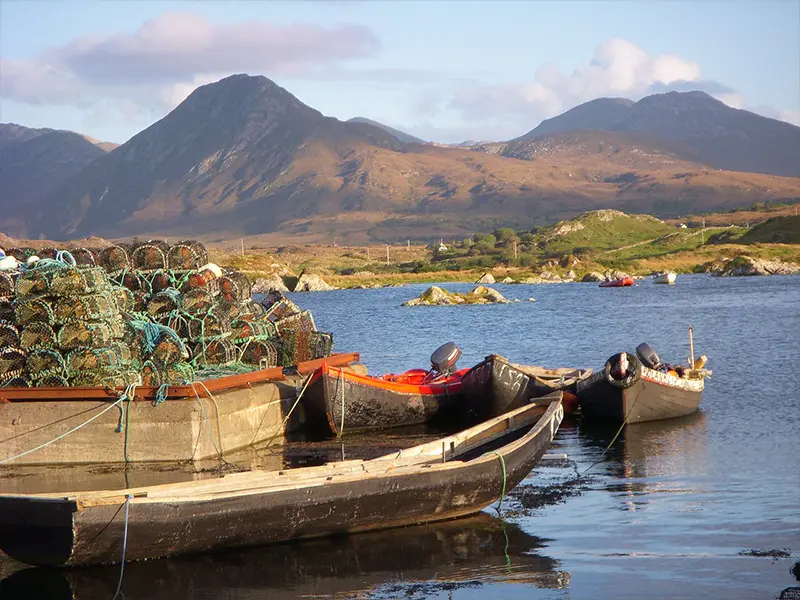 Fiskebåd i hav ved bjerge