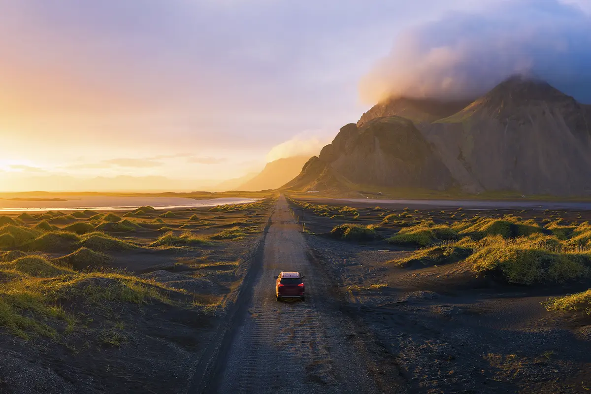 billist kører i Island mod solnedgang