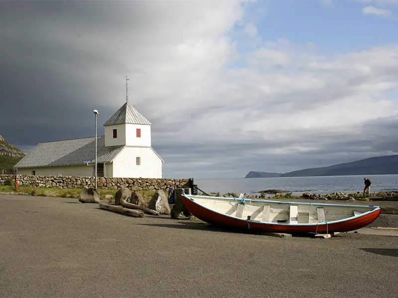 Kirkjubøur ved havnen med en båd ved siden af en kirke