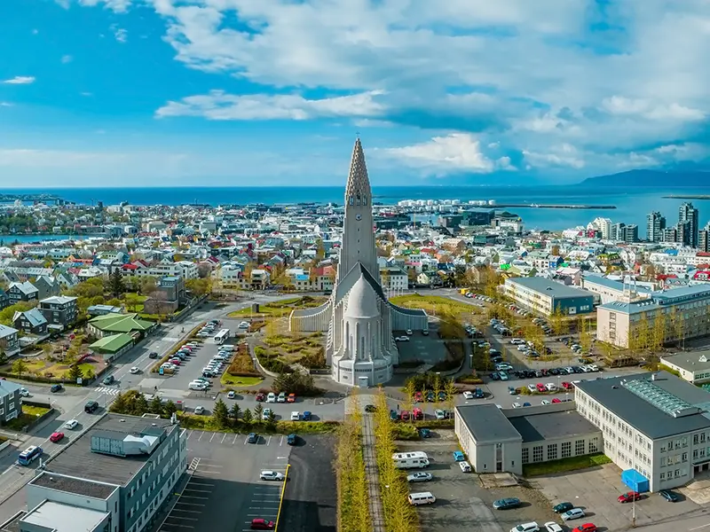 høj kirke med byen omkring sig og blå himmel med skyer